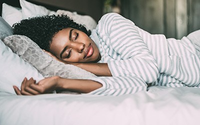 Woman in striped shirt sleeping in bed