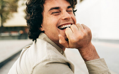 young man sitting outsite on cloudy day and laughing