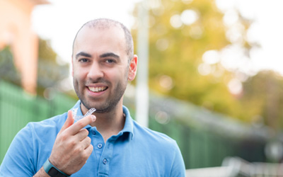 Man in blue shirt about to put in Invisalign aligner