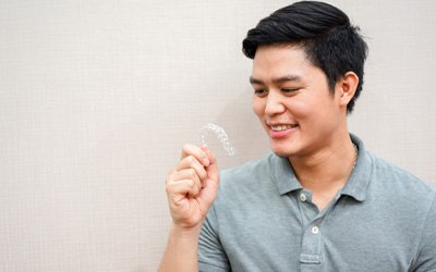 Young man looking at aligner for Invisalign in Wayland, MA 