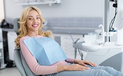 Blonde woman sitting in dental chair and smiling