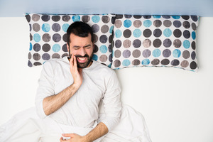 Man lying in bed with jaw pain